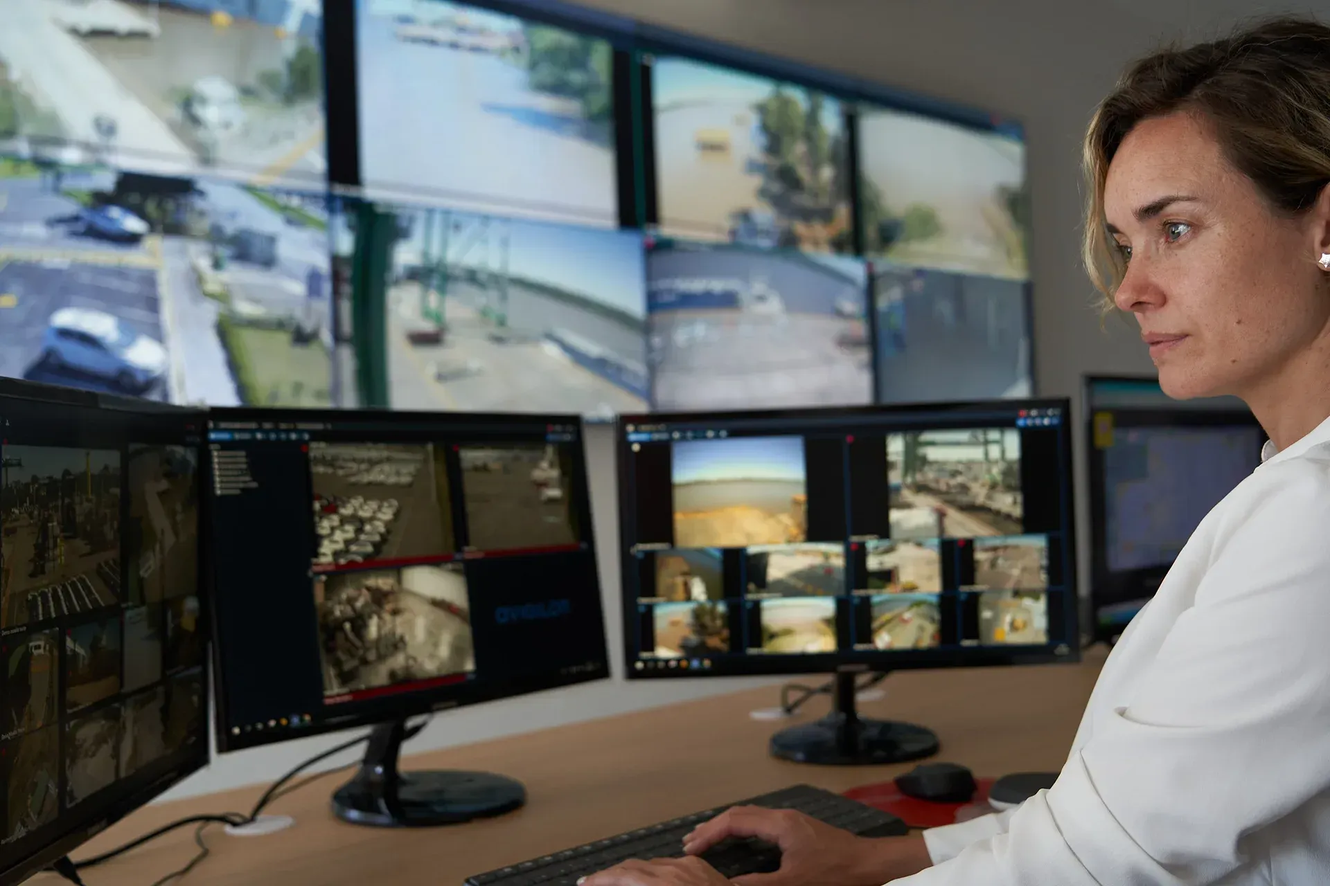 Operator monitoring multiple surveillance screens in a control room