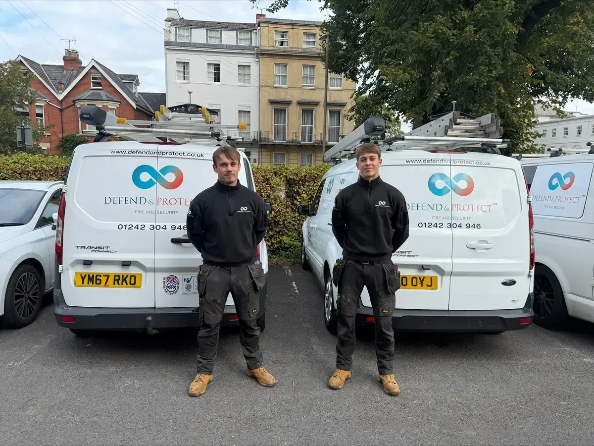 Defend and Protect employees Brandon and Kai standing in front of their work vans