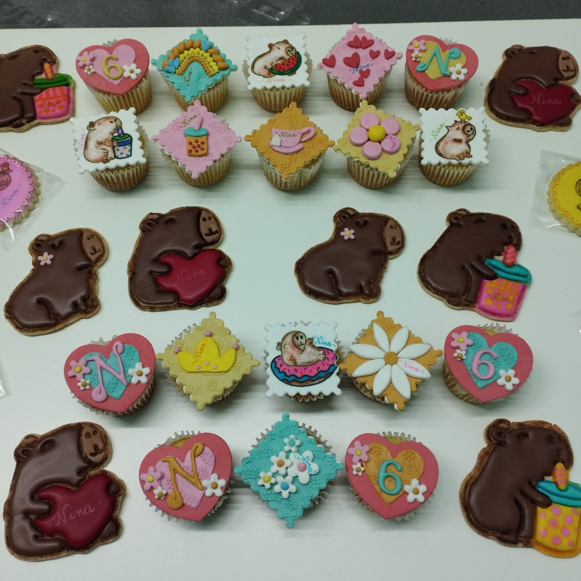 Galletas variadas decoradas con corazones, flores, ositos y glaseado de colores, dispuestas en una bandeja blanca.