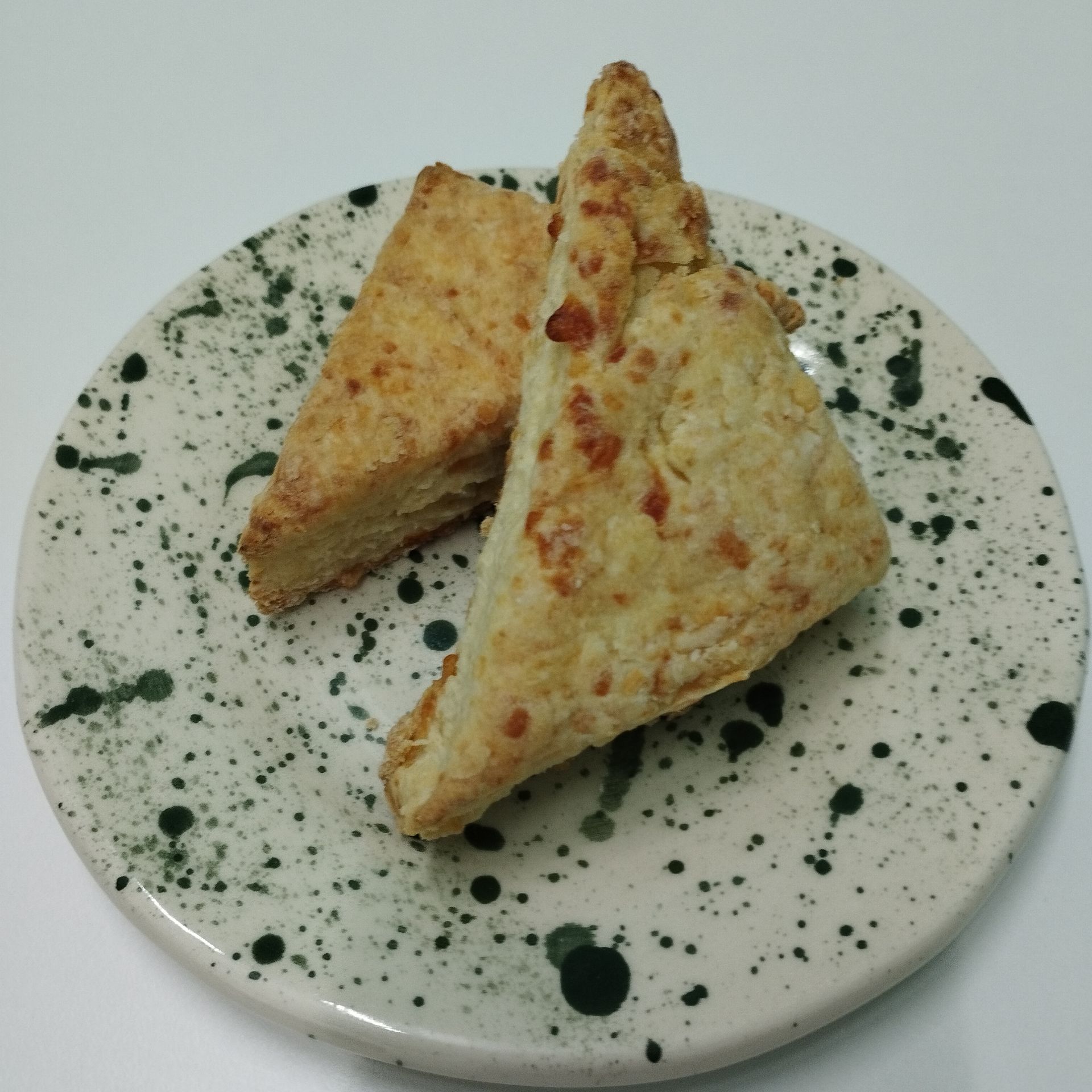 Bollos de queso triangulares en una cesta, con superficies doradas y trocitos de queso naranja.