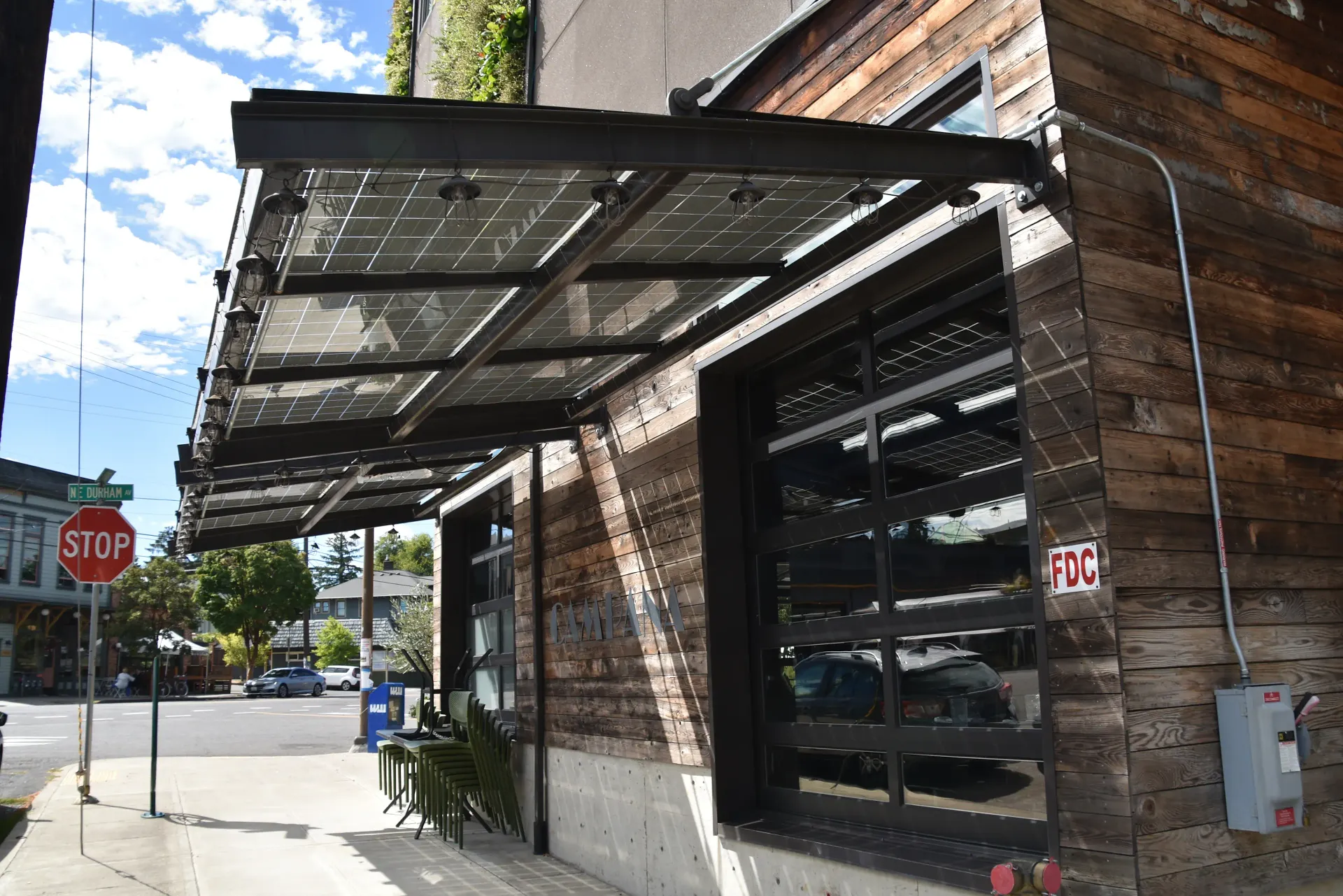 Brick storefront with black awning and large window on a sunny street corner