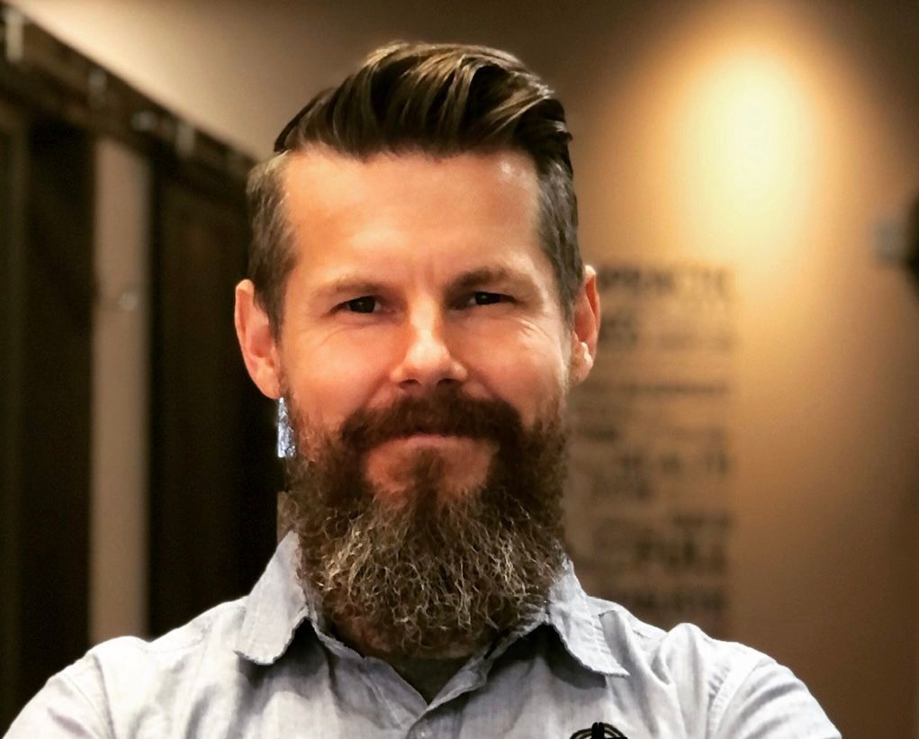 Dr. Ben Tapper - Portrait of a bearded man smiling in a softly lit indoor setting