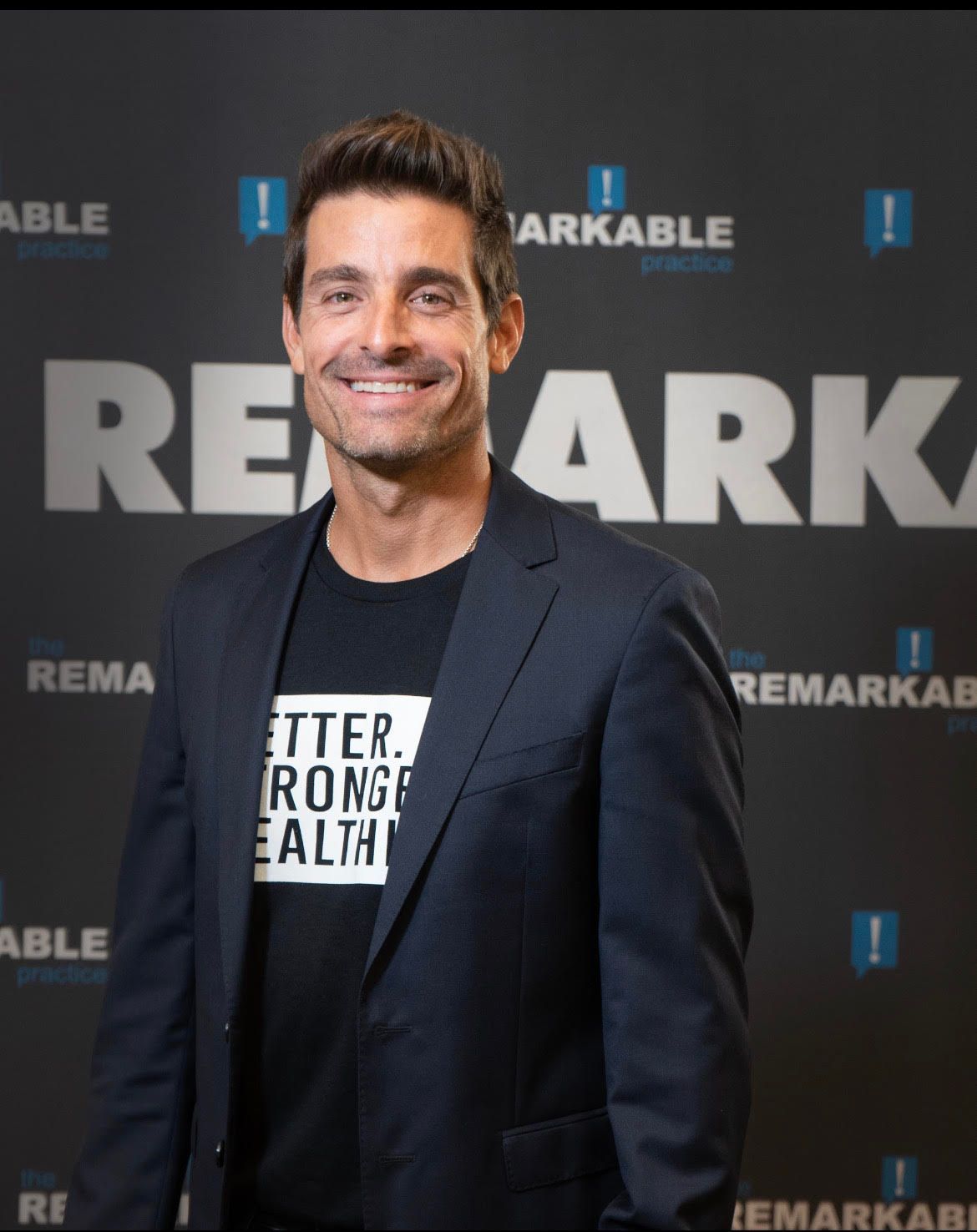 Dr. Sebastian Gonnin - Man in a navy blazer smiling at a Remarkable event backdrop