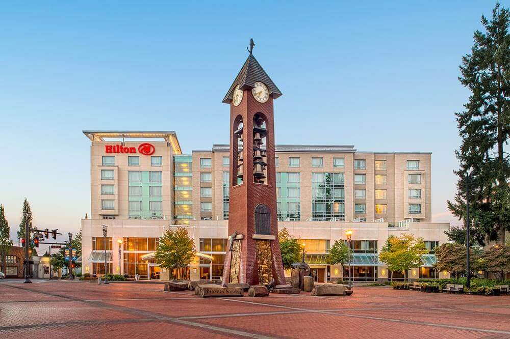 A large Hilton building with a clock tower in front of it.