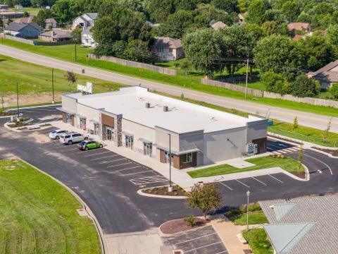 Aerial view of a small commercial building with a parking lot and surrounding roads.