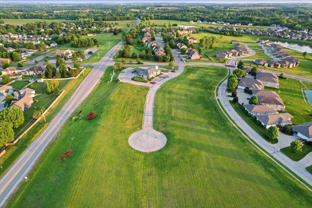 Aerial view of a suburban neighborhood with a large green park and curving paved path.