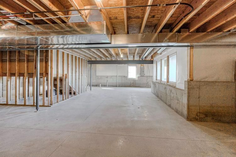 Unfinished basement interior with exposed framing, concrete floor, and ductwork overhead.