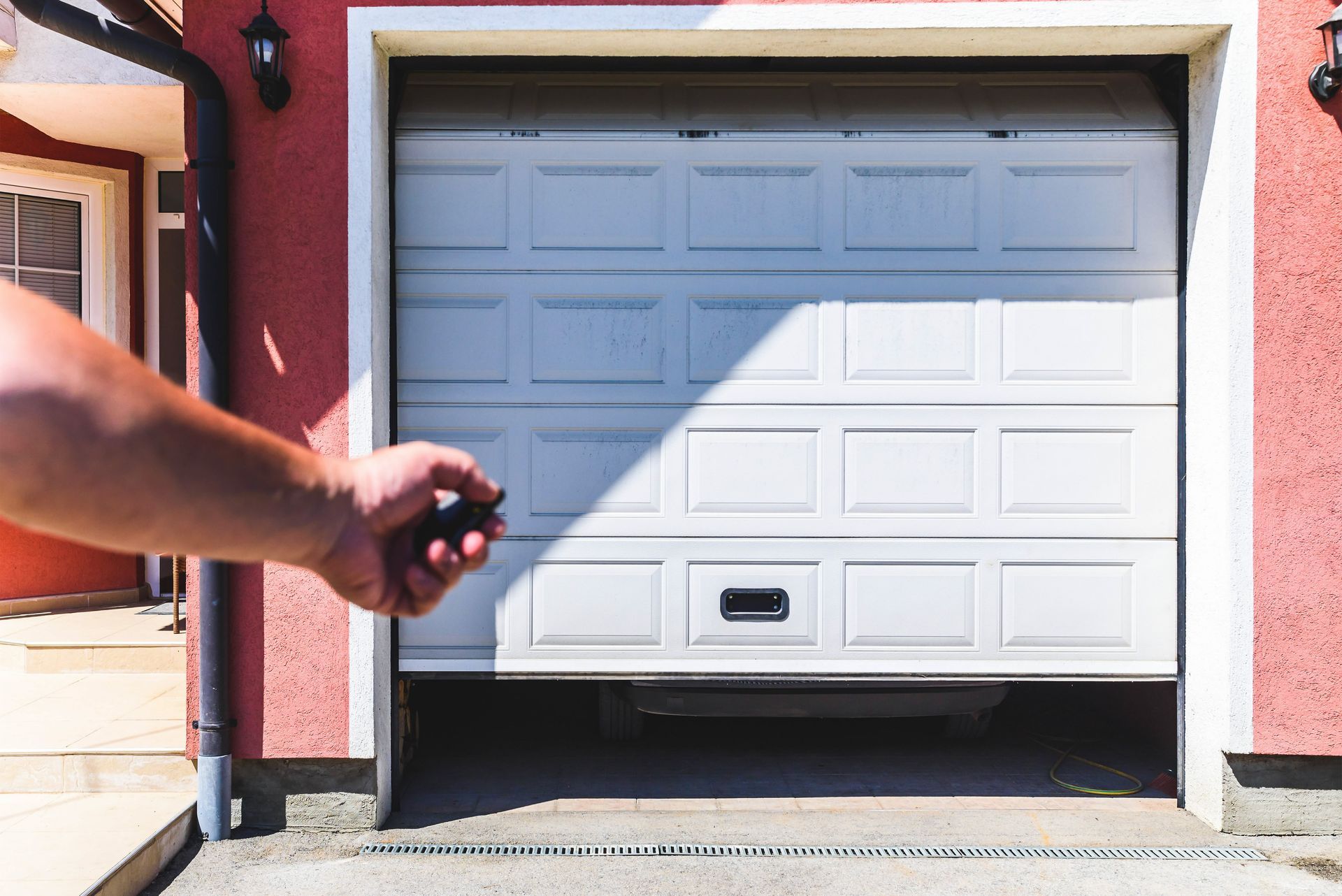 A person is opening a garage door with a remote control.