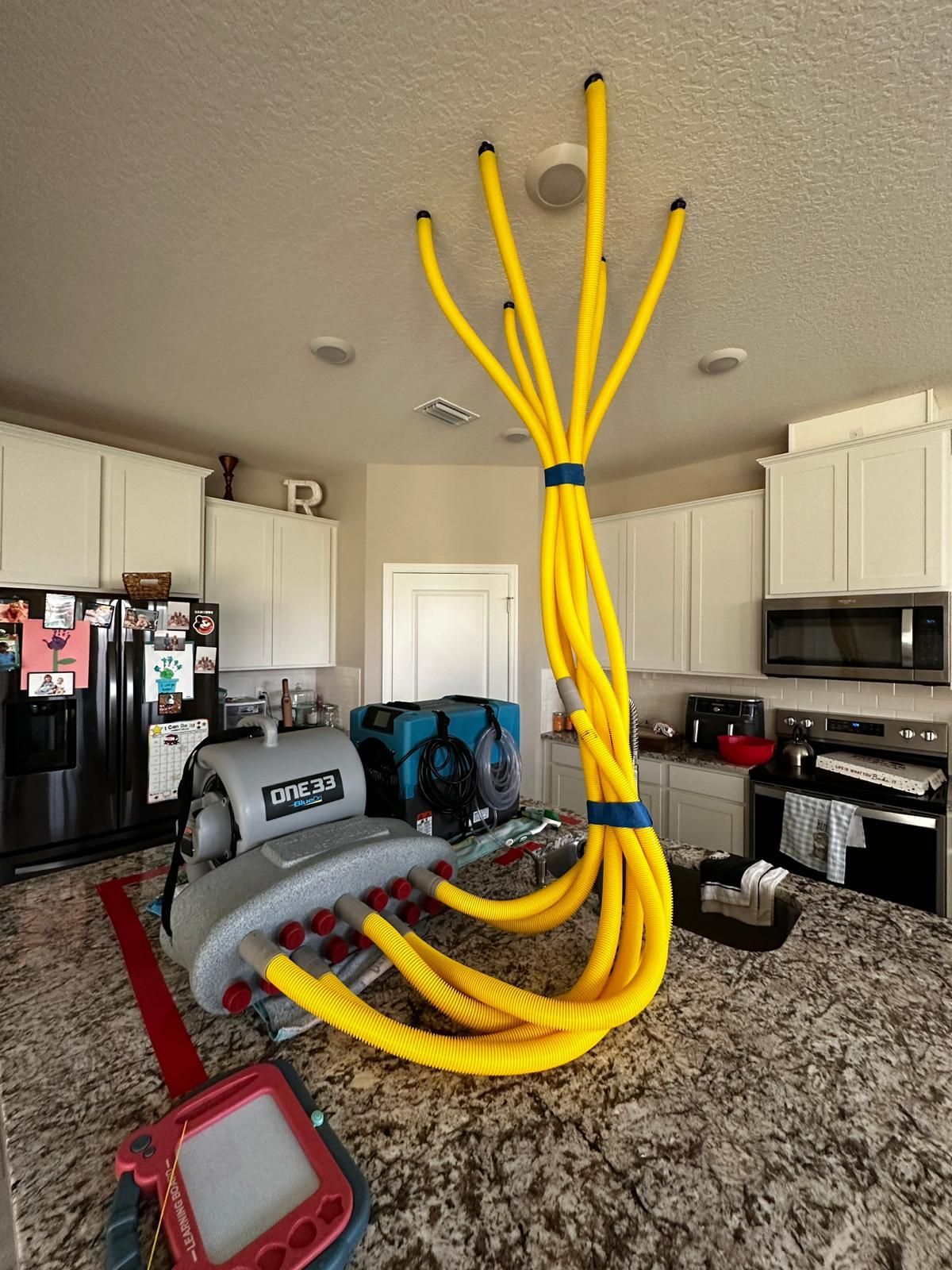 A kitchen with a bunch of yellow hose hanging from the ceiling
