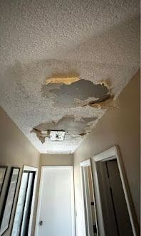A hallway with a ceiling that has been damaged by water.