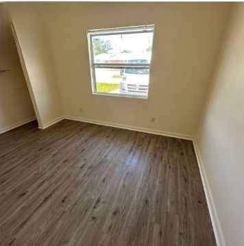 An empty room with hardwood floors and a window.