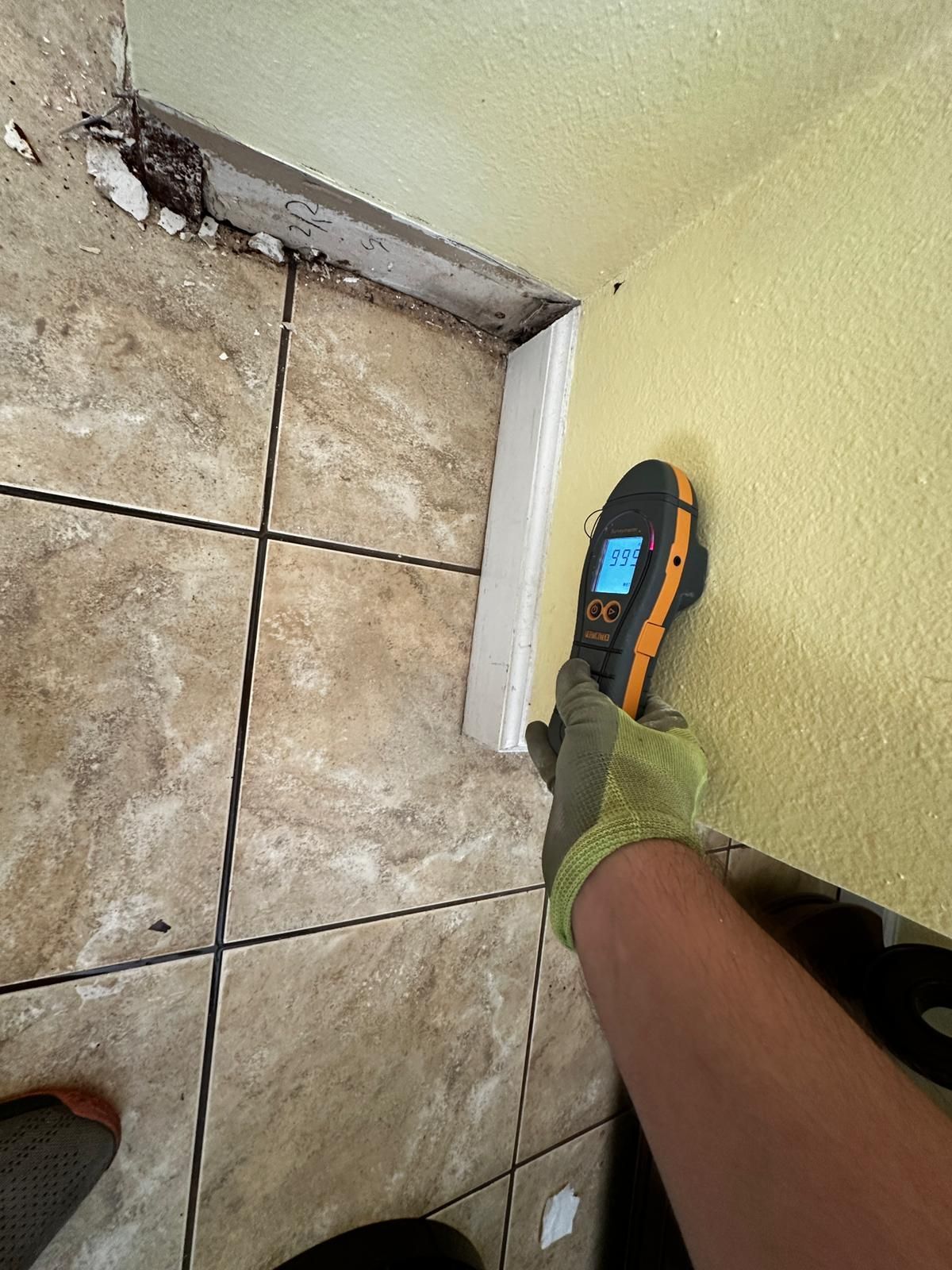 A person is using a thermometer on a tiled floor.
