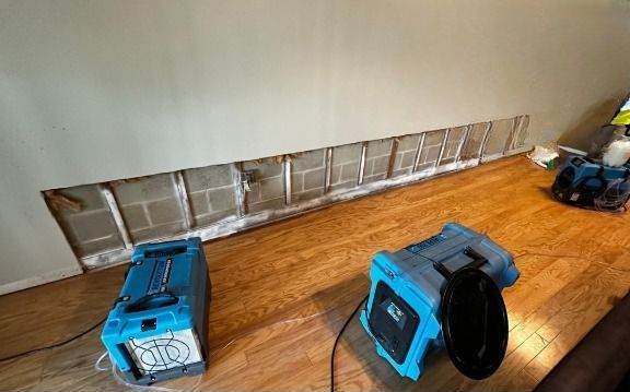 Two blue appliances are sitting on a wooden floor next to a wall.
