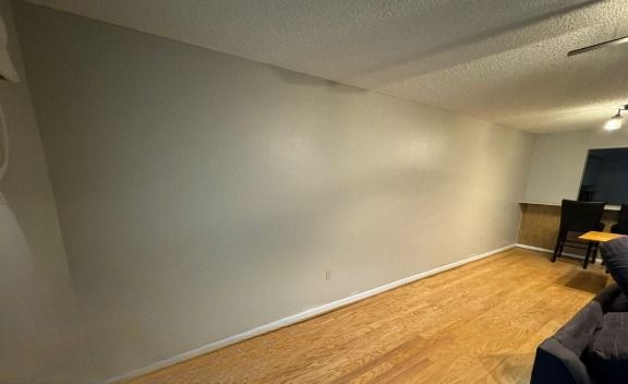 A living room with hardwood floors , a couch and a desk.