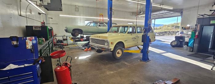 Yellow classic car in an auto repair garage with tools, lifts, and another car in the background | Cripple Creek Automotive Tire and Towing
