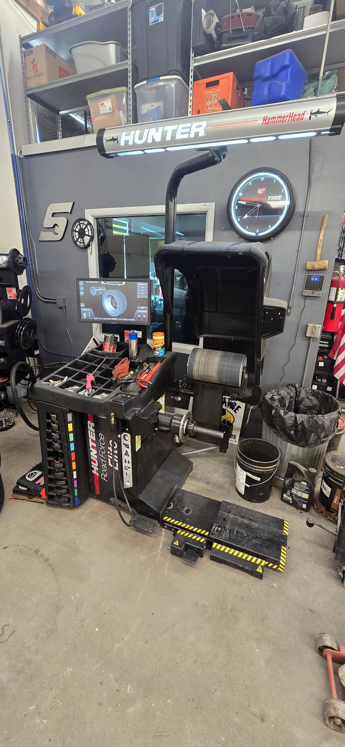 Garage workshop with a black racing simulator rig, steering wheel, pedals, monitor, and tool storage. | Cripple Creek Automotive Tire and Towing