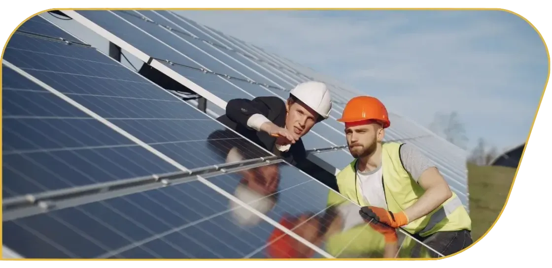 Two workers inspecting rooftop solar panels, one in white helmet and one in orange hard hat.