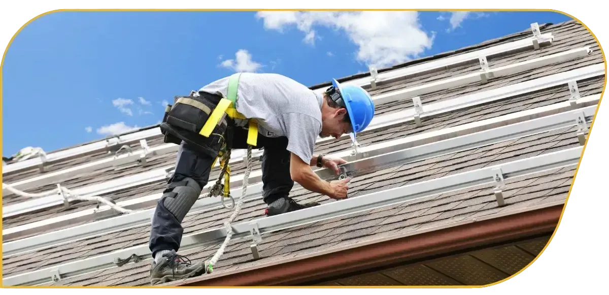 Worker in blue hard hat fastening metal panels on a sloped roof.