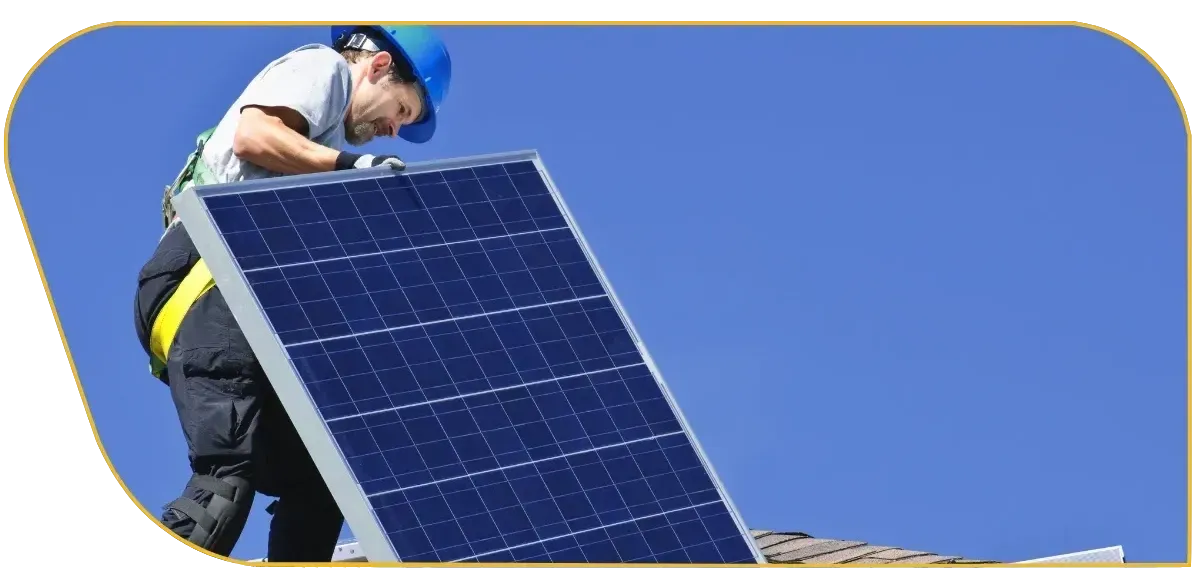 Worker installing a solar panel on a roof under a clear blue sky