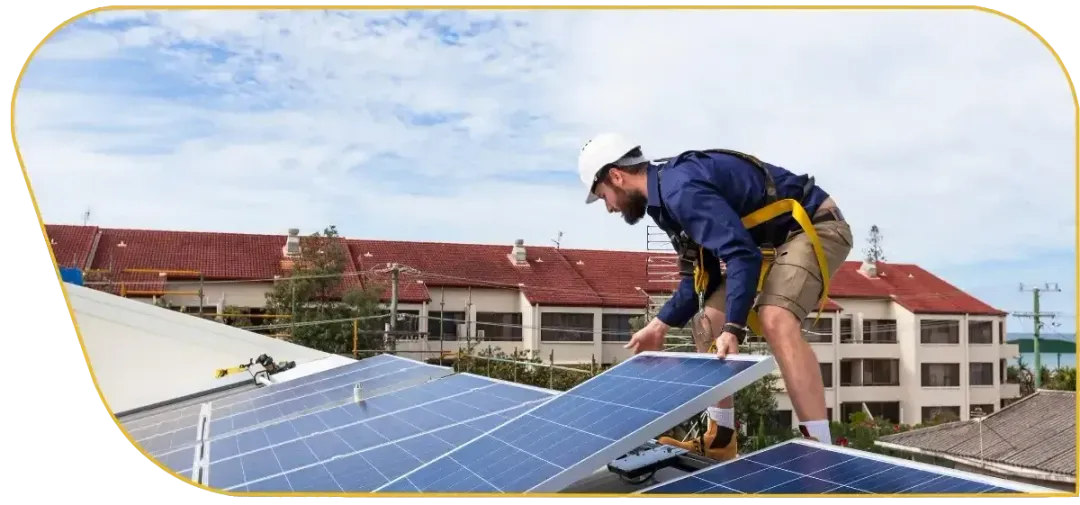 Worker installing solar panels on a rooftop with buildings in the background