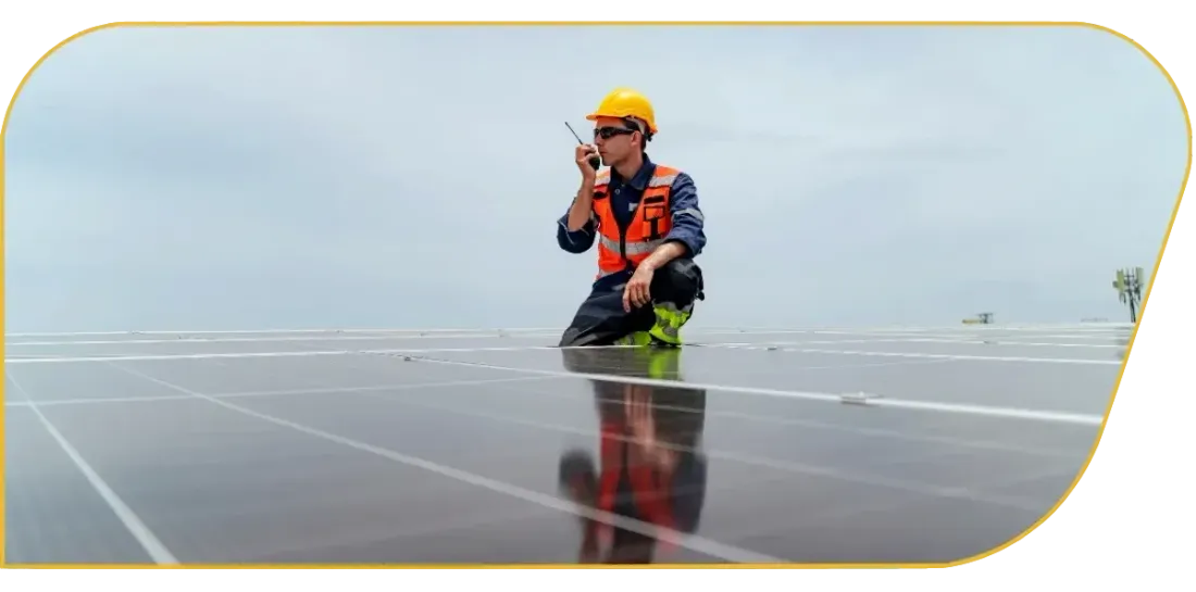 Worker in hard hat inspecting solar panels in a field