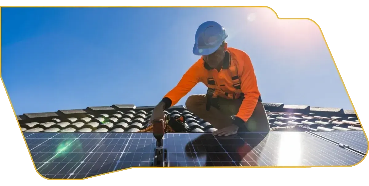 Worker installing solar panels on a rooftop under a blue sky