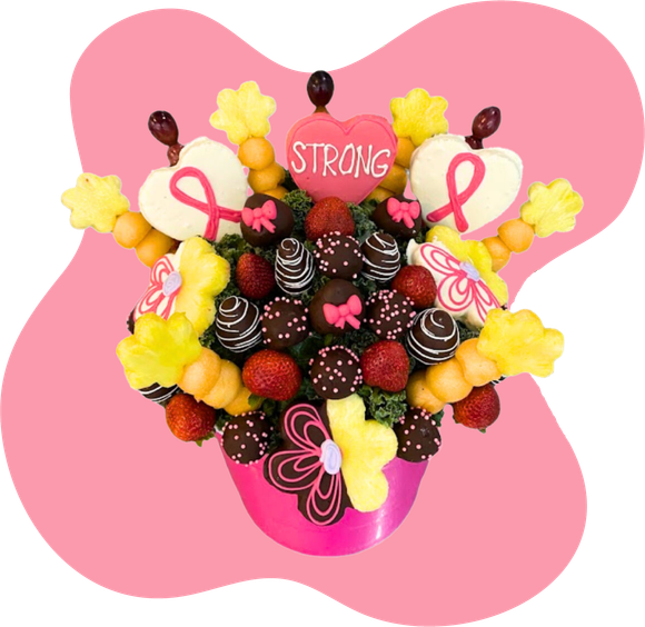 Pink floral fruit bouquet with strawberries, grapes, pineapple, chocolate-covered treats, and a “STRONG” topper