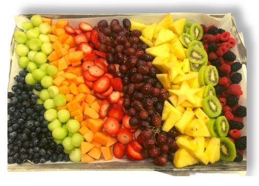A tray of fruit is arranged in a rainbow pattern