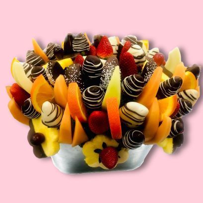 A bowl filled with chocolate covered fruit on a pink background