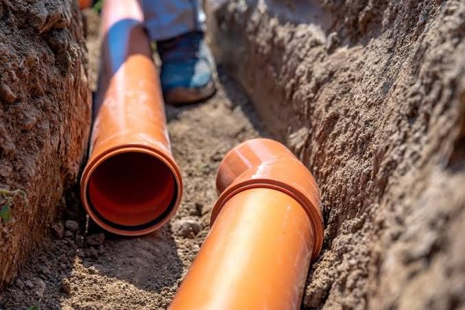 Orange PVC pipes laid in a trench for underground utility installation