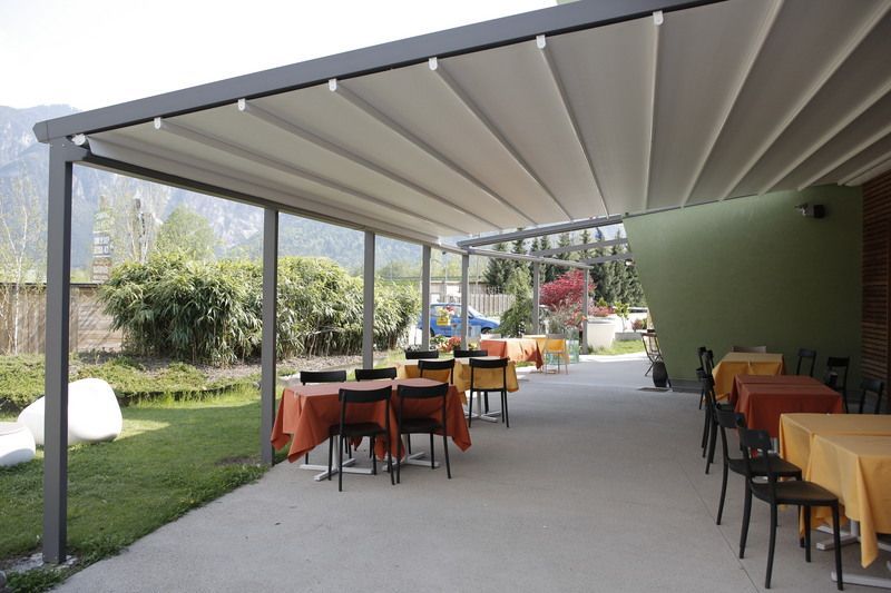 Outdoor restaurant patio with retractable canopy, tables, and chairs.