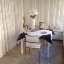A white table set for dining with a black tablecloth. A vase of white flowers sits in the center.