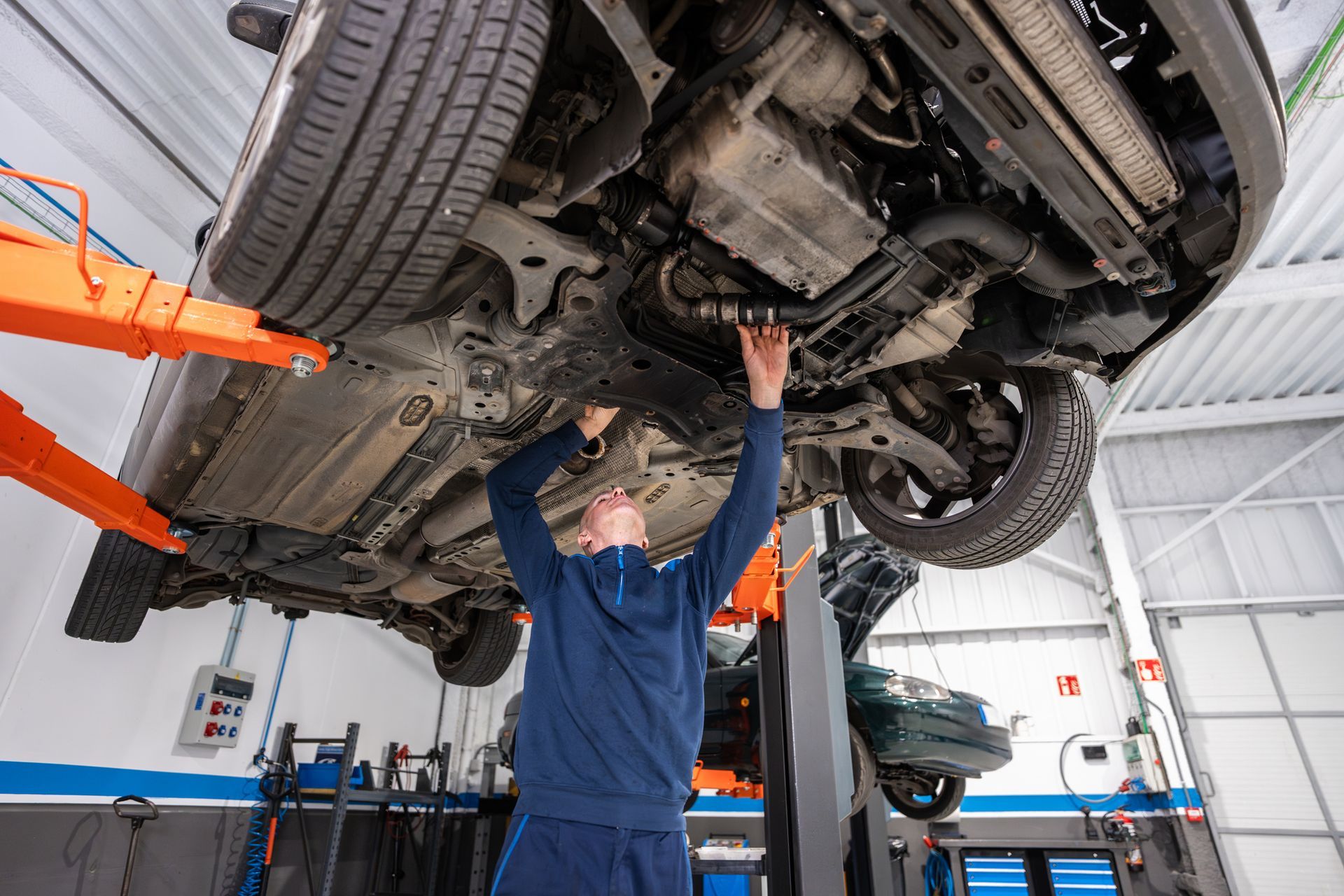 Mechanic working on a car raised on a lift in a garage.