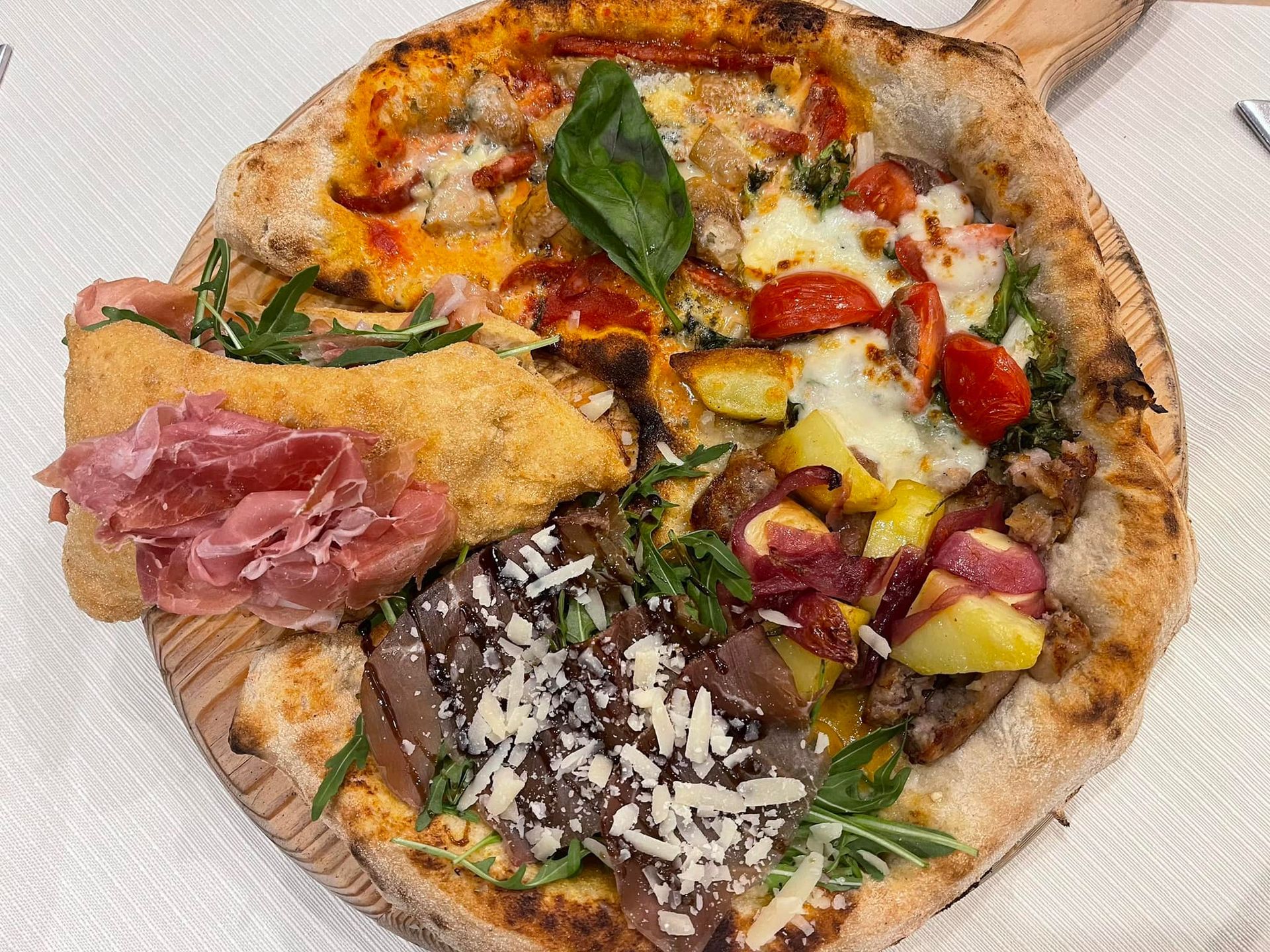 Pizza con vari condimenti su tagliere di legno.