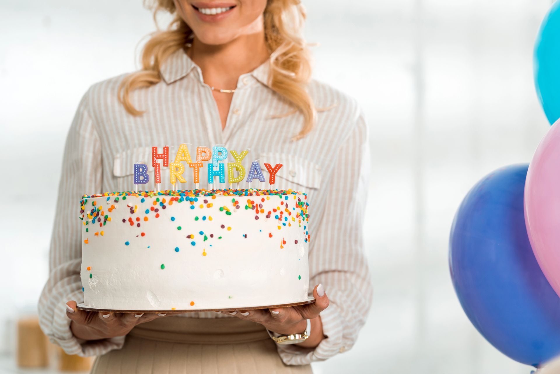 Persona che tiene in mano una torta di compleanno con le candeline