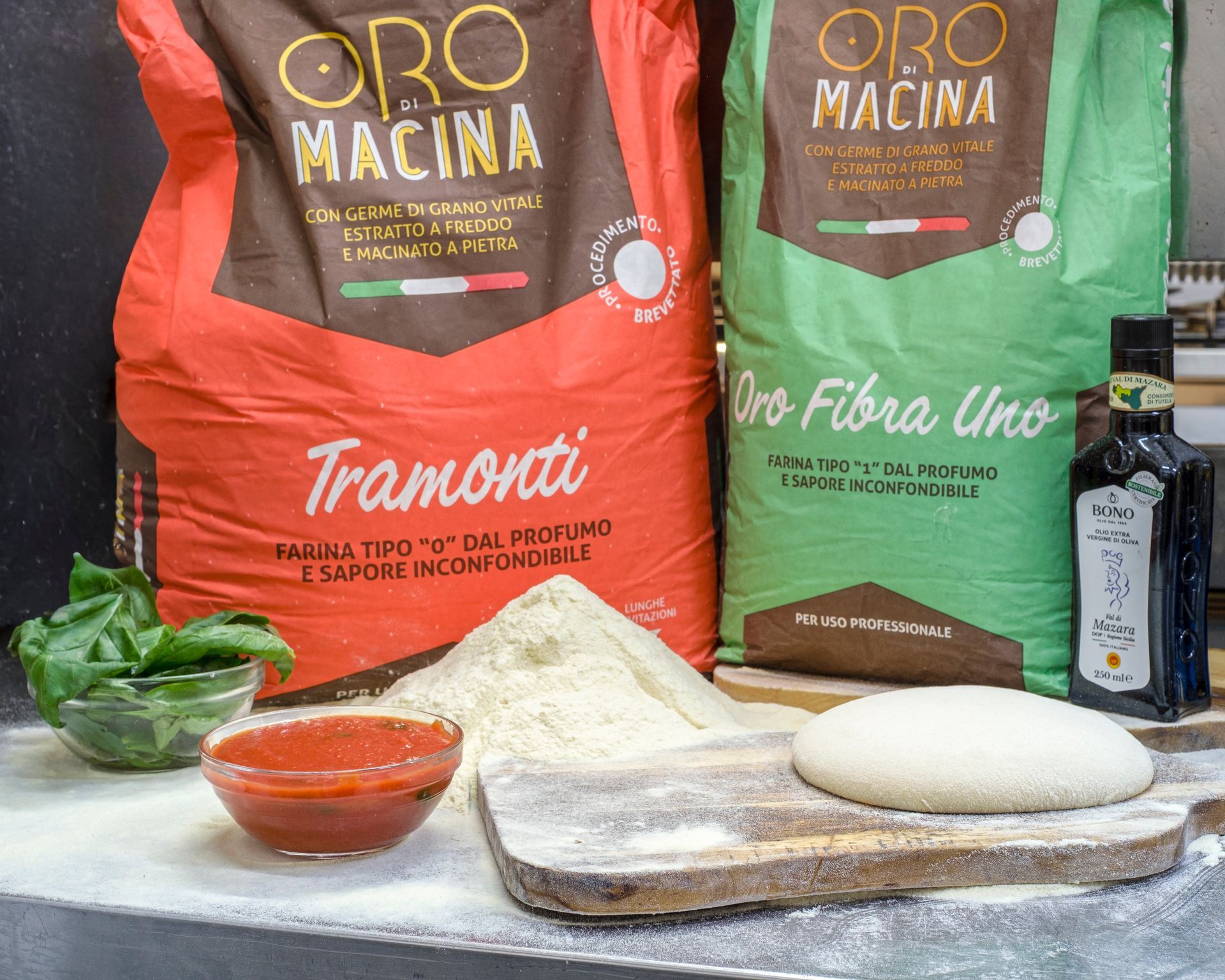 Tagliere di legno con pasta fritta guarnita con vari ingredienti, vino e bicchieri su una tovaglia bianca.