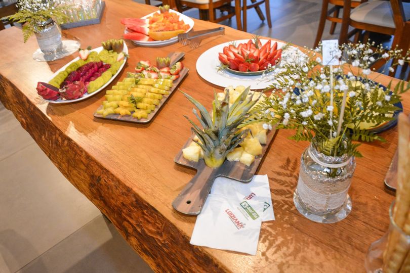 Mesa de madeira com diversas frutas cortadas e arranjos de flores. Chalé Mont Hermon.