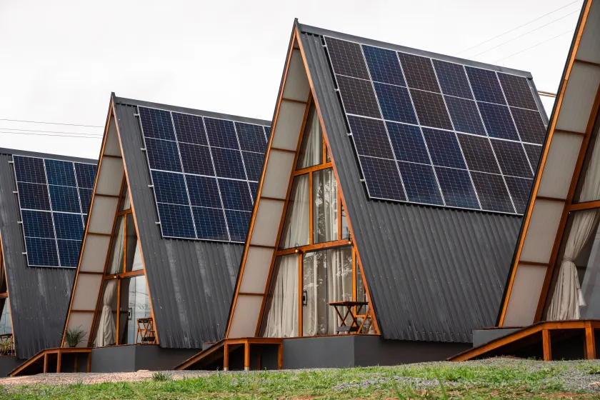 Cabanas em formato de A com painéis solares nos telhados, em um campo gramado. Chalé Mont Hermon.