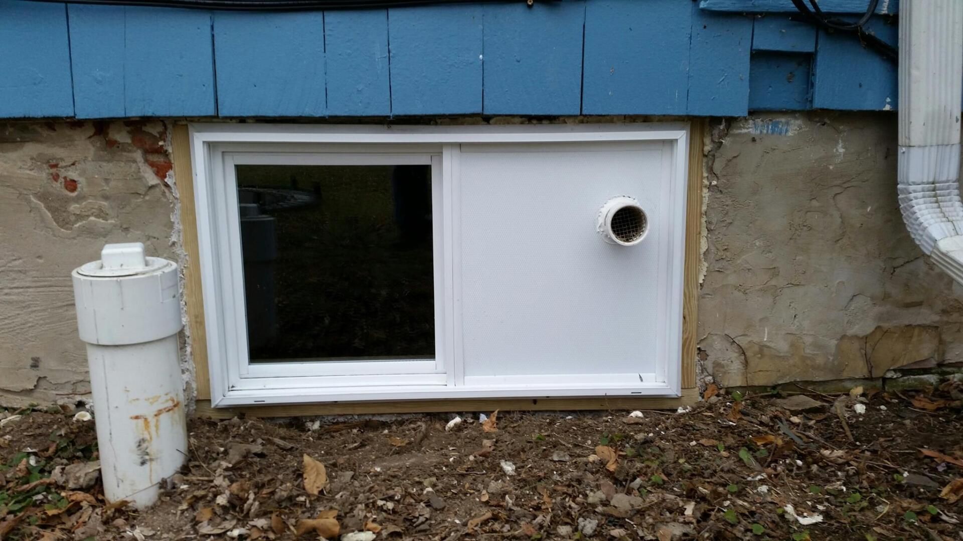 There is a window in the basement of a house.