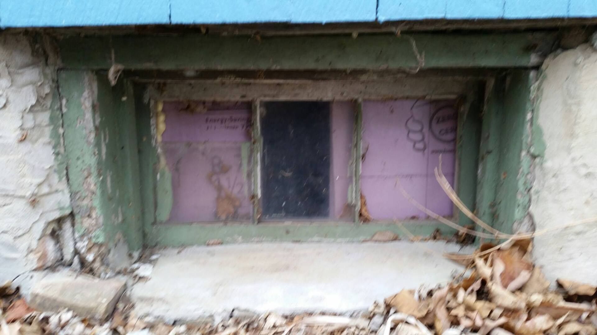 There is a window in the basement of a house.