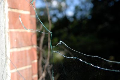 A broken glass window is sitting on a brick wall.