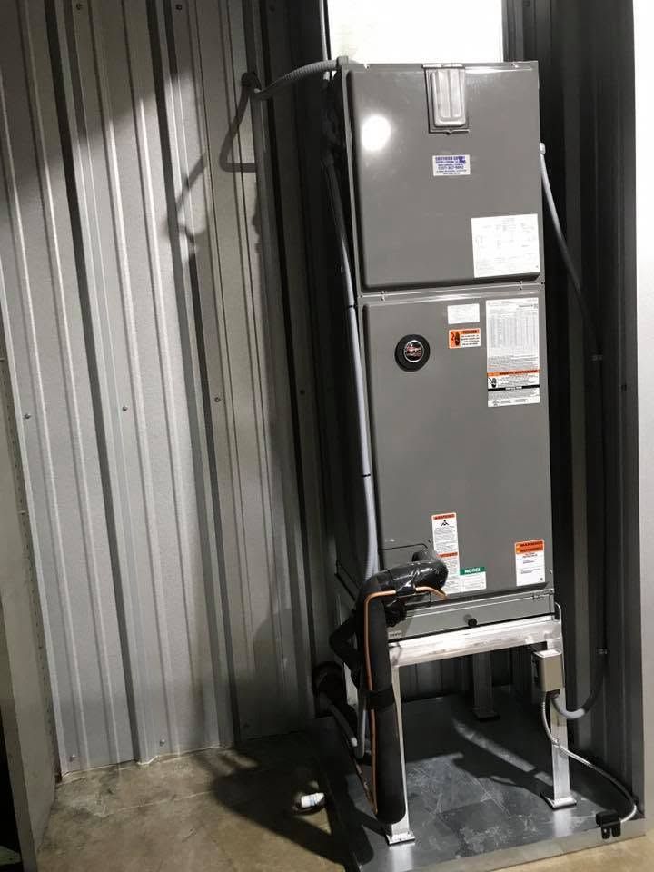 Gray HVAC unit on a metal platform against corrugated metal walls inside an industrial room