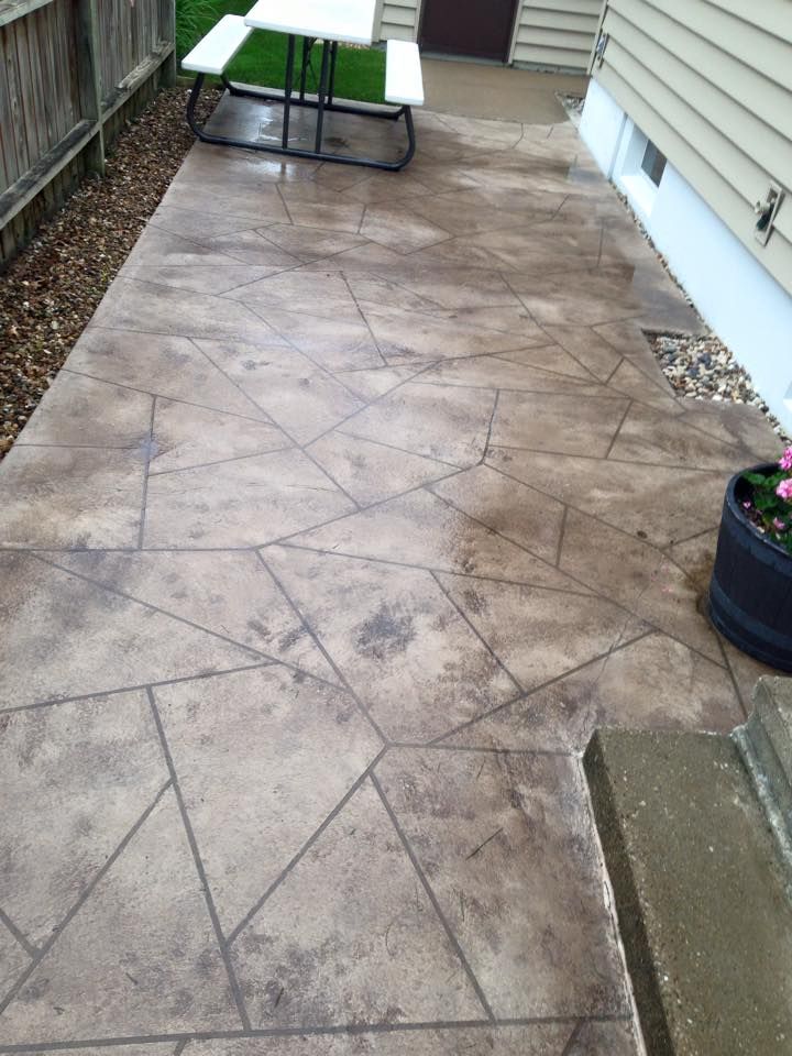 Patio with decorative concrete, picnic table, and flower pot next to a house.