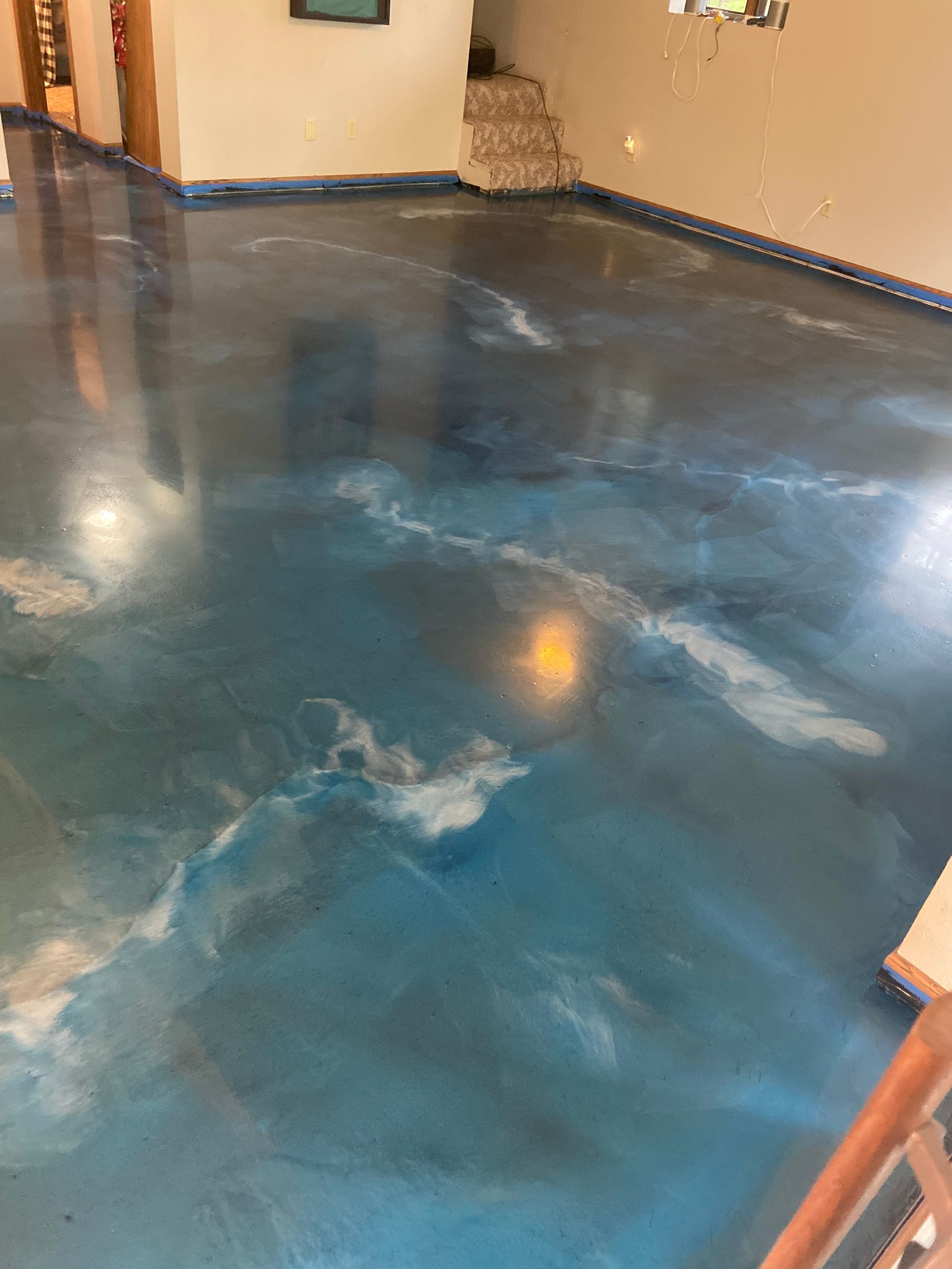 Blue and white marbled epoxy floor in a room, reflecting light.