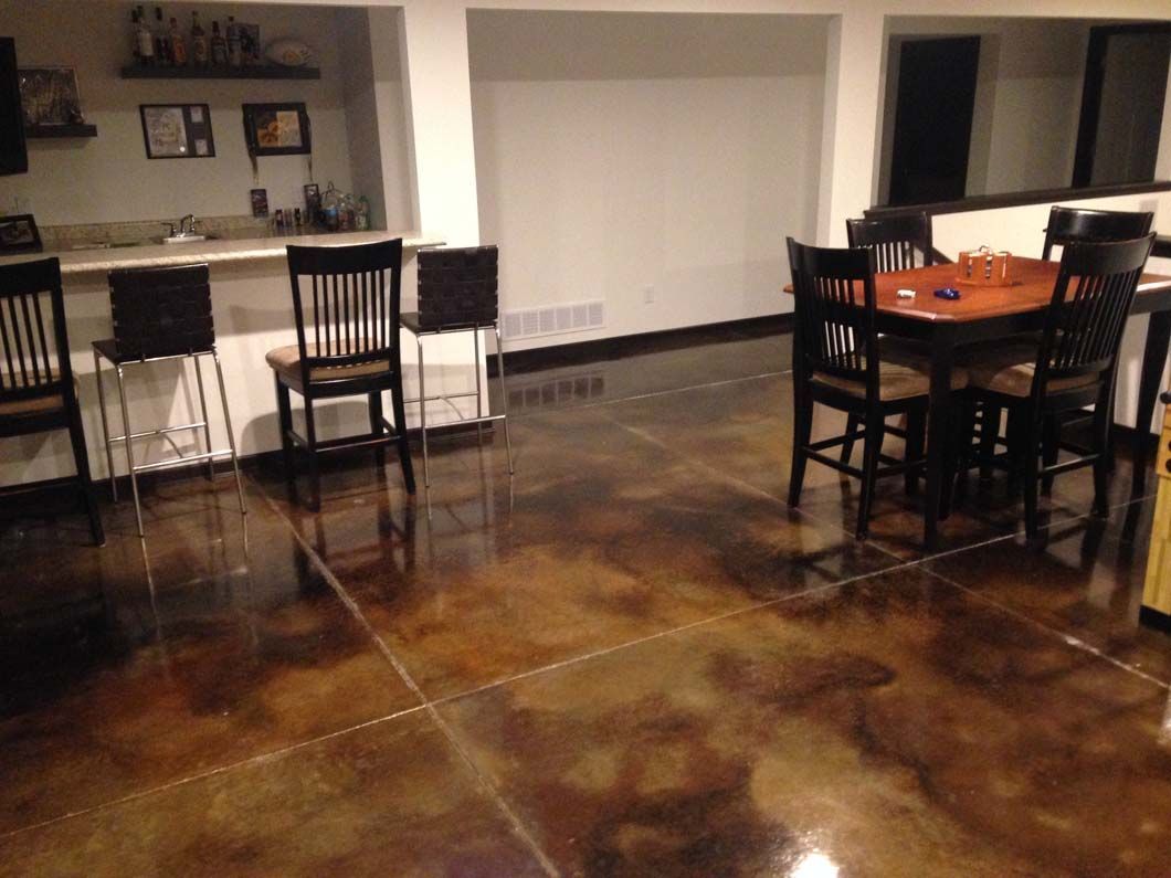 Bar and dining area with shiny stained concrete floor, dark wood furniture, and neutral walls.