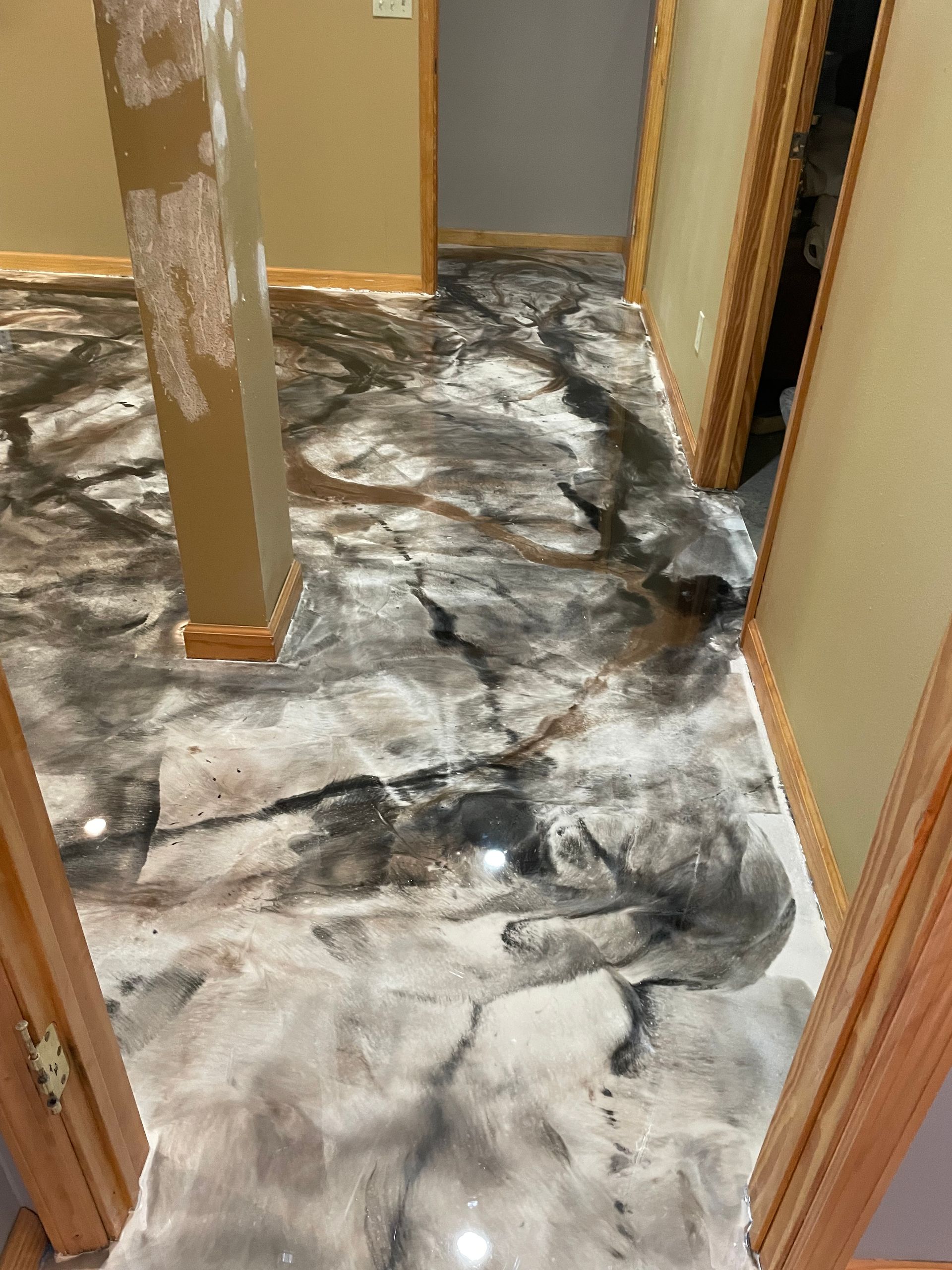 Epoxy floor with gray, black, and white marble-like design in a hallway.