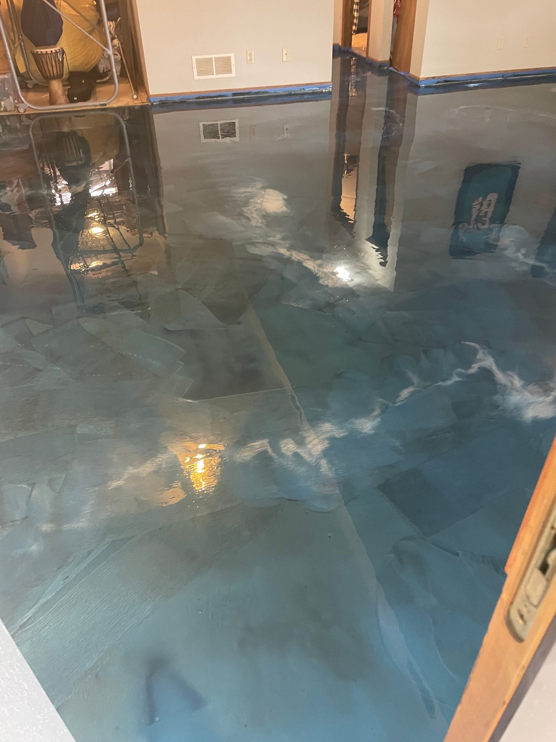 Metallic blue epoxy flooring, reflecting room and lights, installed indoors.