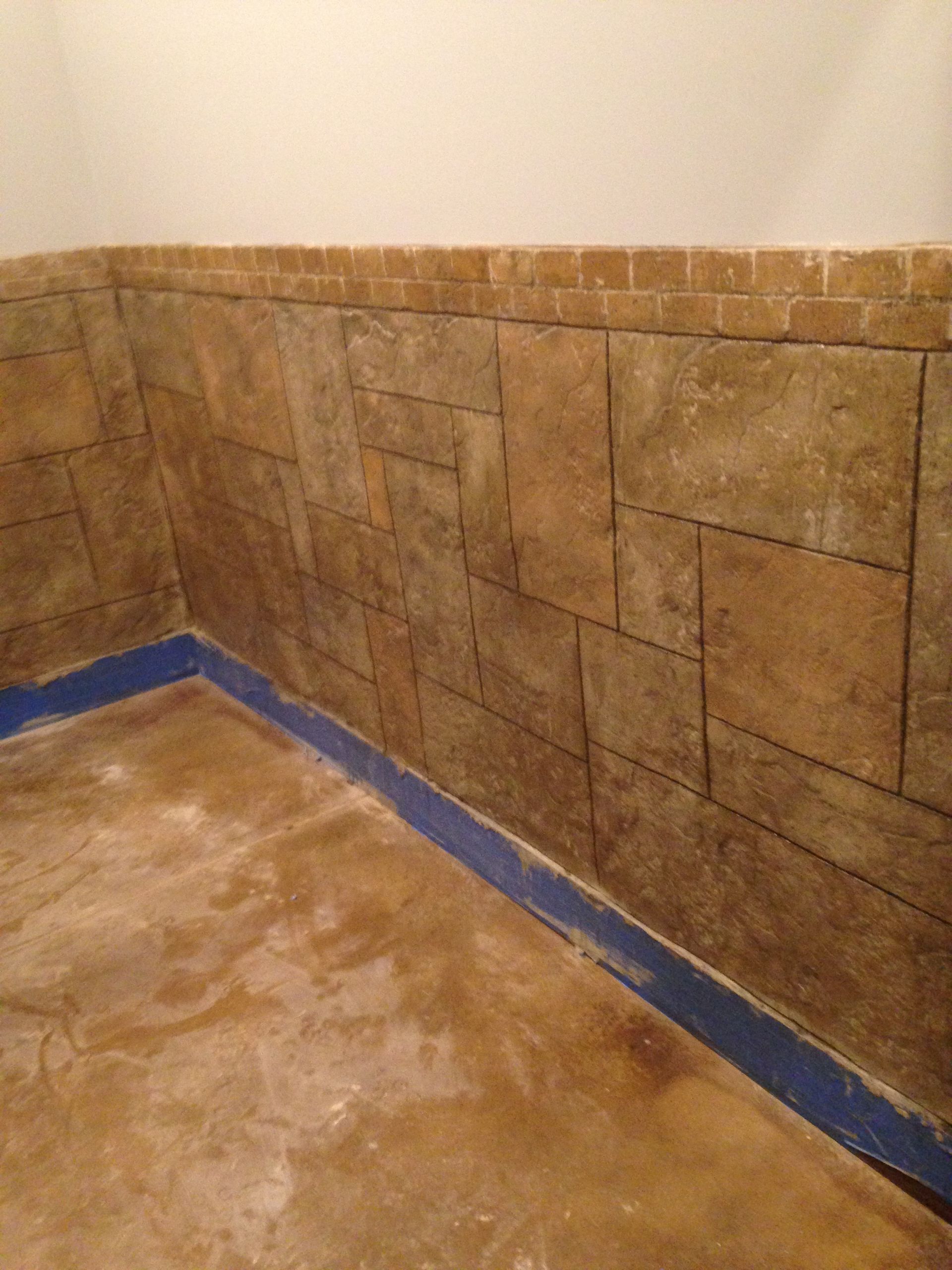 Corner of a room with textured tan walls and blue trim, concrete floor.