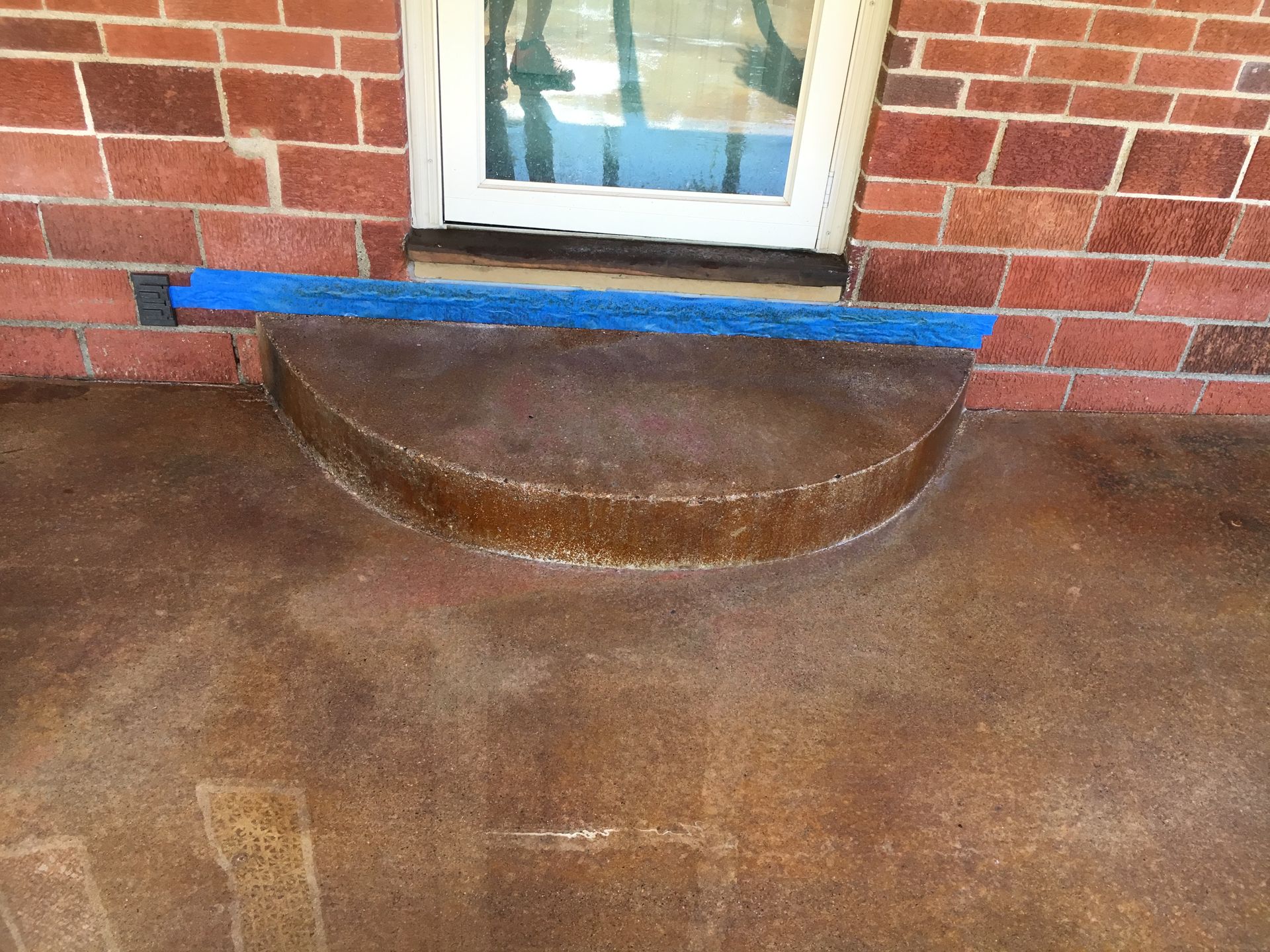 Brick building entrance with a curved step and blue mat.