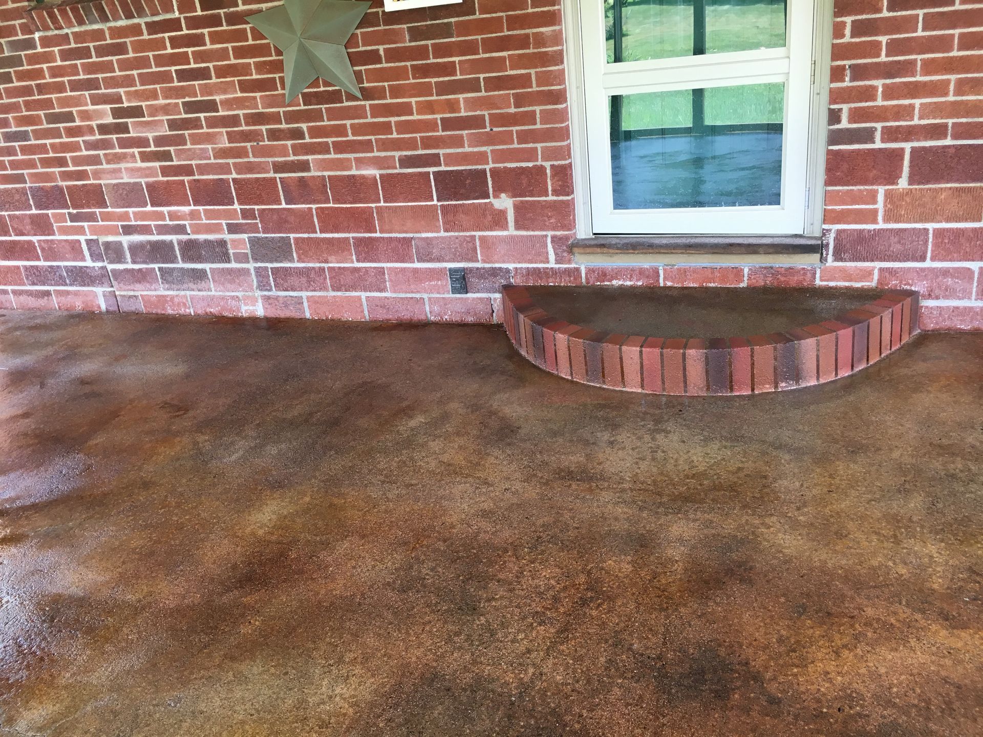 Brick exterior with stained concrete porch and brick step leading to a window.